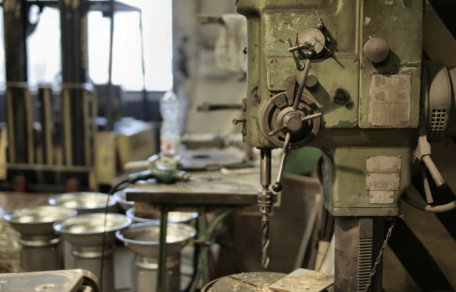 Das Foto zeigt eine mechanische Werkstatt mit einer Standbohrmaschine.