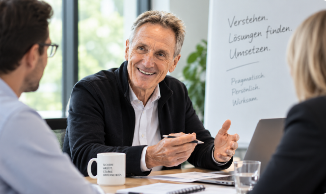 Ulrich Hillebrand im Beratungsgespräch zur Arbeitssicherheit mit zwei Beschäftigten in einem modernen Büro.